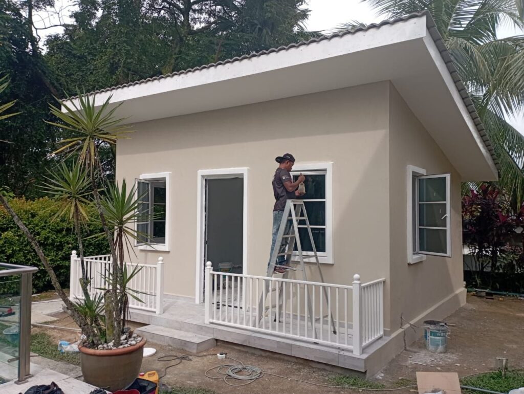Worker finishing exterior painting on a house extension near Bangsar South