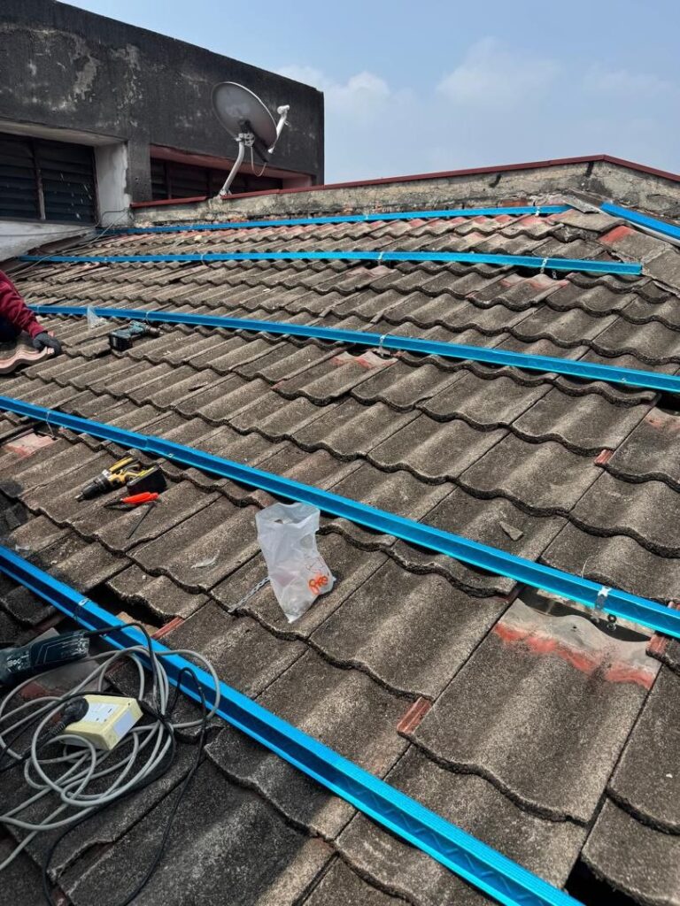 Roofer installing mounting rails over tile roofing during a roof repair job in Taman Sri Puchong