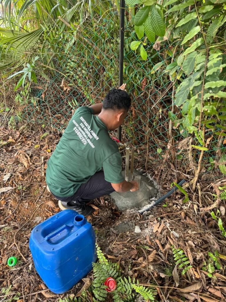 Plumber setting new water meter riser pipes in cement during meter relocation in Petaling Jaya