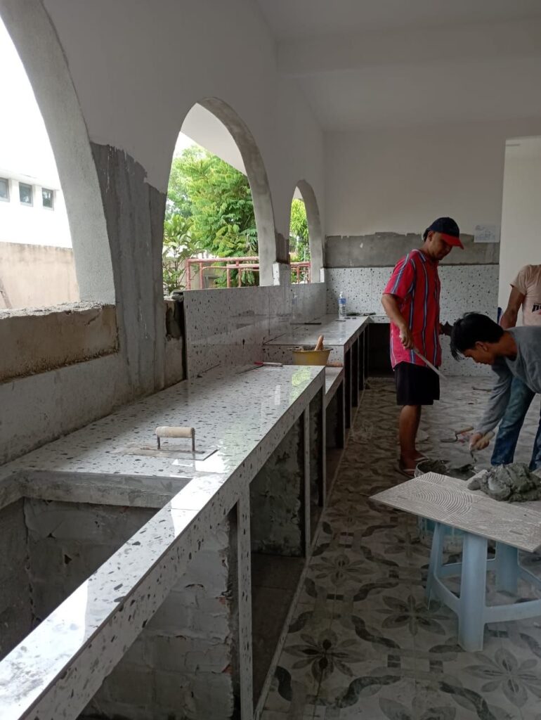 Contractor plastering and tiling an outdoor terrace counter during a renovation in Taman Bandar Sunway