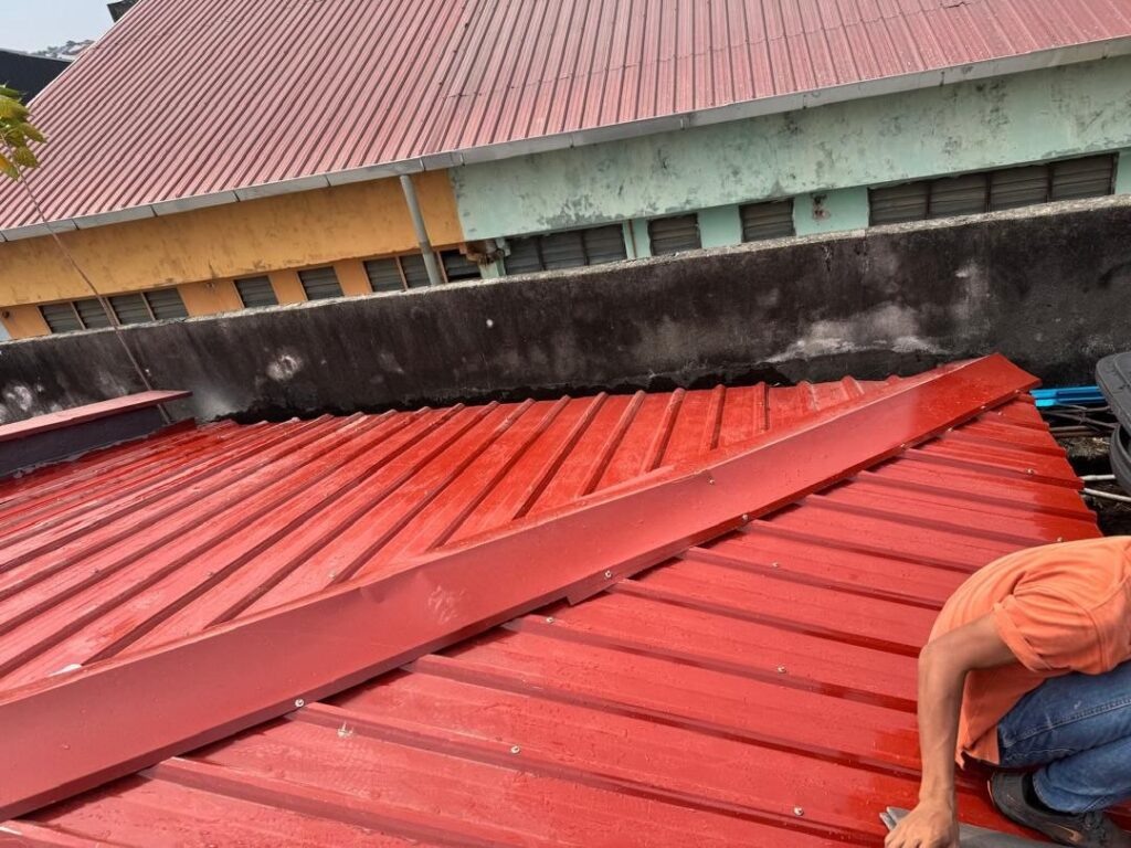 Worker repainting a metal roof during a roofing service job in Taman Subang SS3