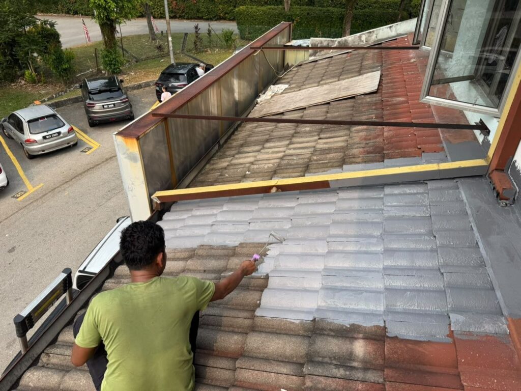 Roofer applying waterproof coating to an ageing tile roof near Kelana Jaya